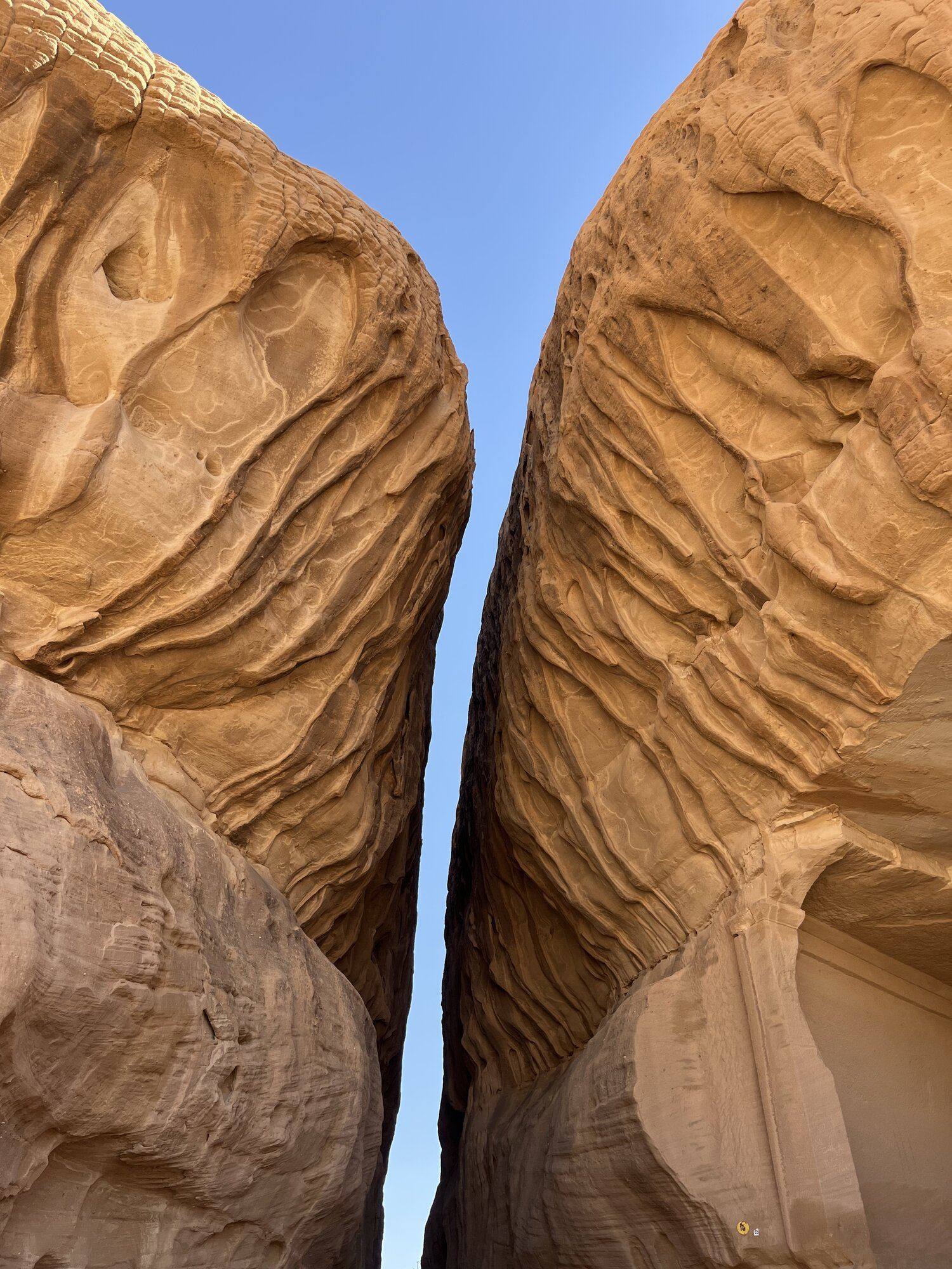 Looking up between two towering sandstone formations in AlUla