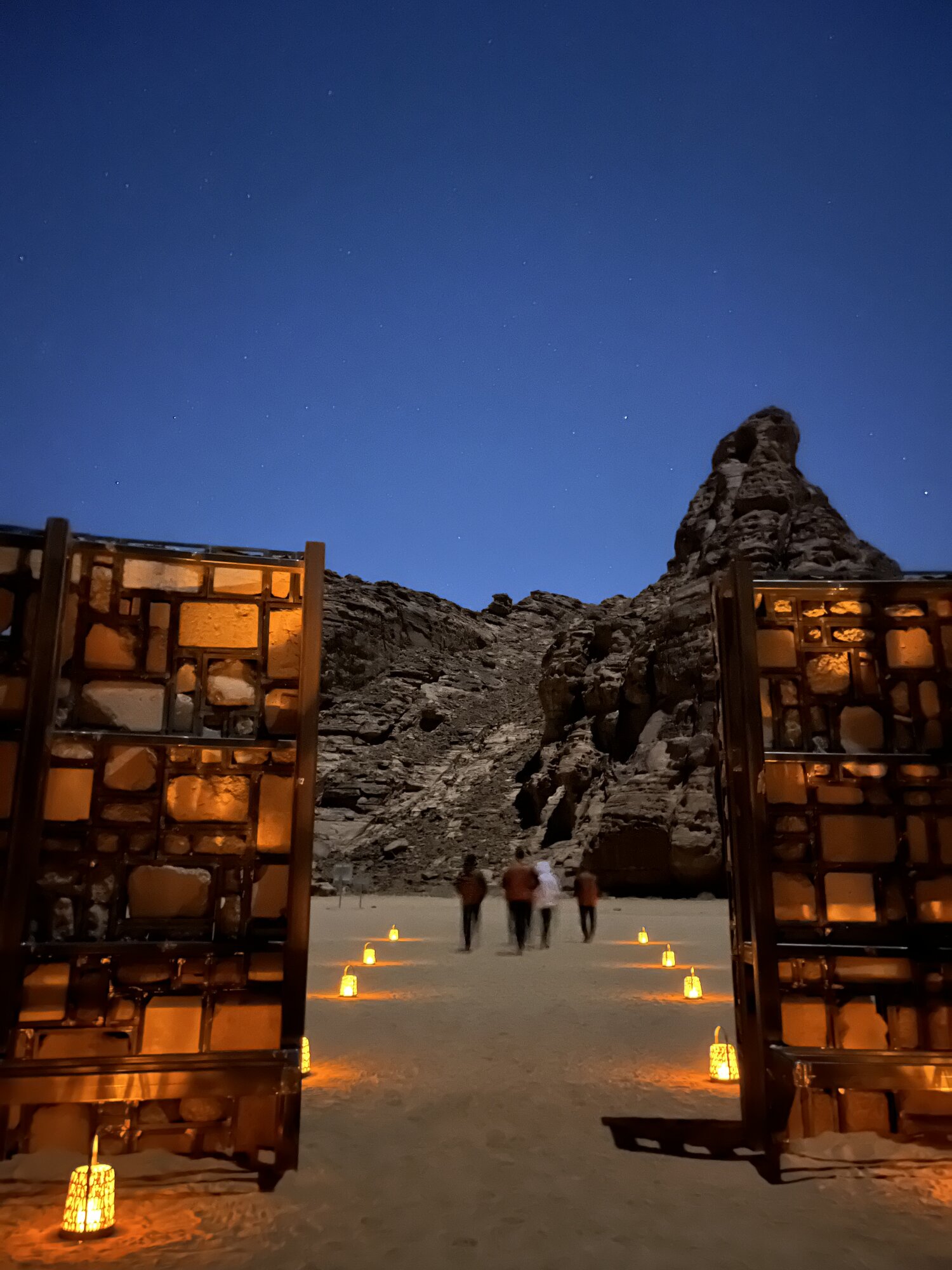 Lantern-lit walkway under a desert sky at night in AlUla