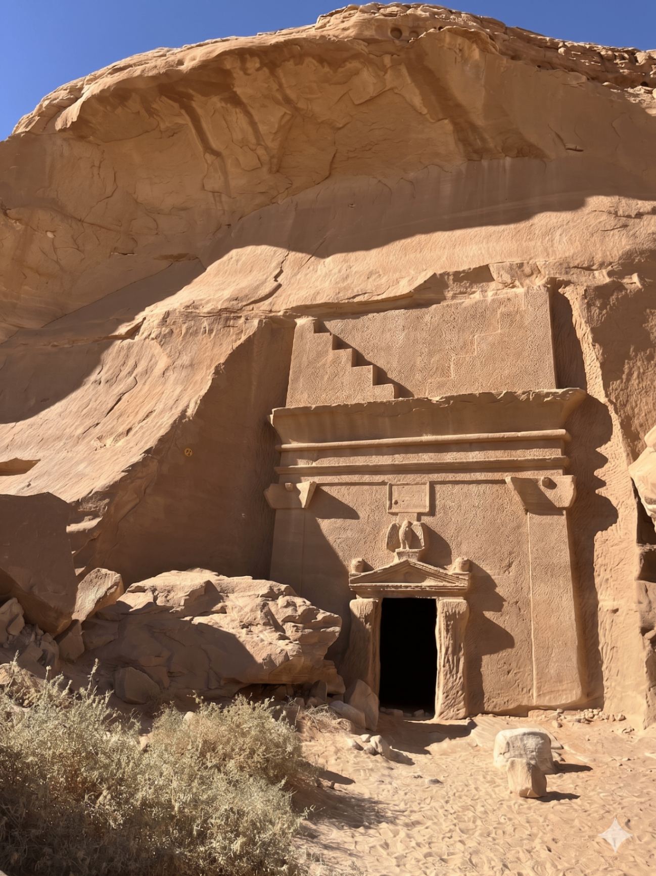 A Nabataean rock-cut tomb at Hegra, carved into a sandstone cliff.